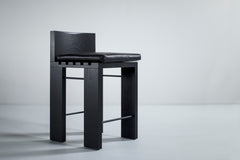 Front view of a black Chile counter stool showing its leather cushion