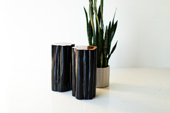 Black outdoor stump tables with natural tops beside a plant