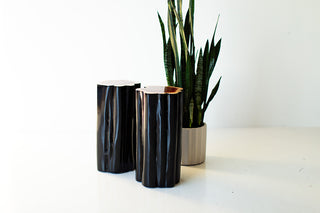 Black outdoor stump tables with natural tops beside a plant