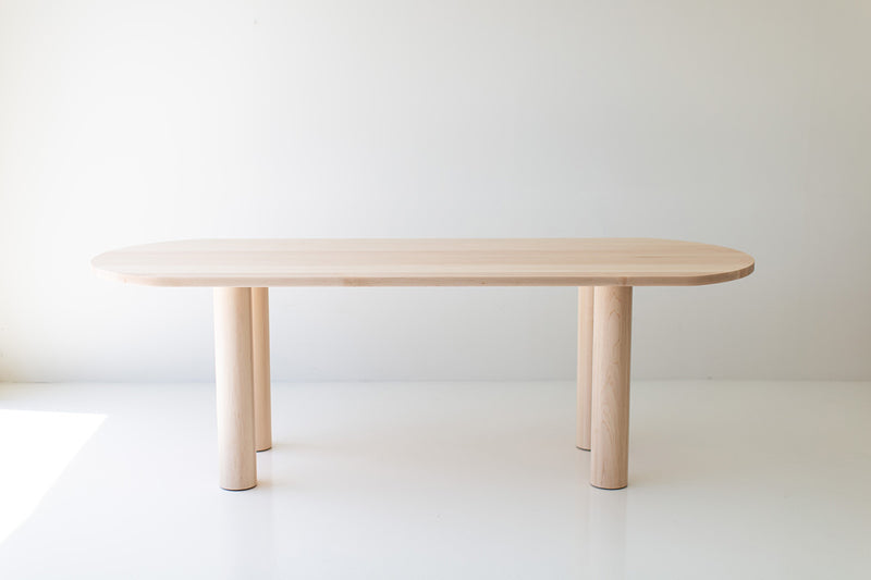Cava modern oval dining table in maple with a long, sculptural pedestal base