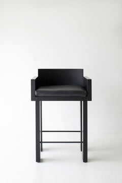Front view of a blackened oak counter stool showing its cushioned seat