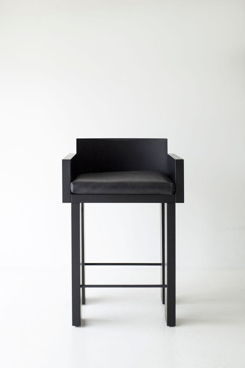 Front view of a blackened oak counter stool showing its cushioned seat