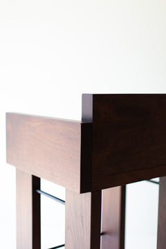 Modern walnut bar stools with arms lined up at a kitchen island