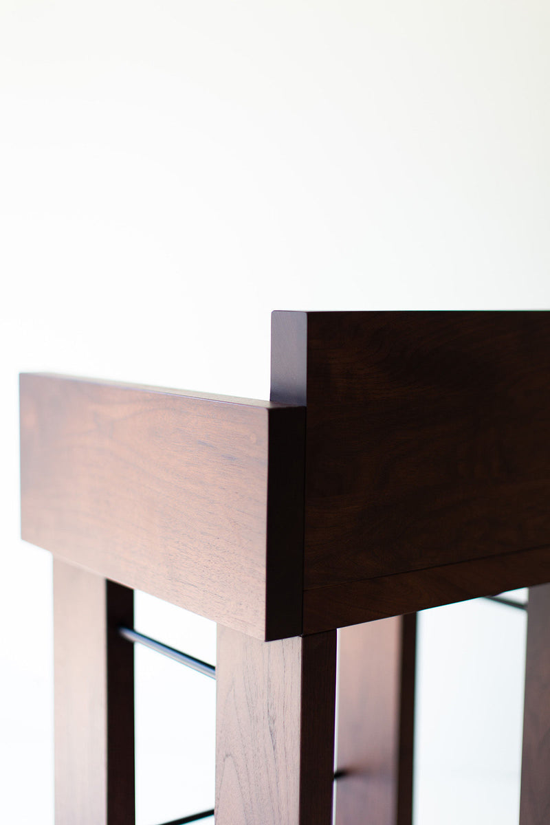 Modern walnut bar stools with arms lined up at a kitchen island