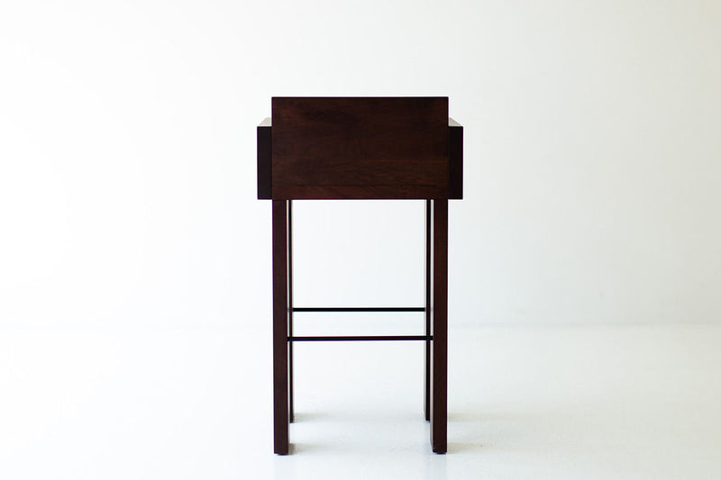Chile modern bar stool seen at an angle, showing the thick walnut frame and arms