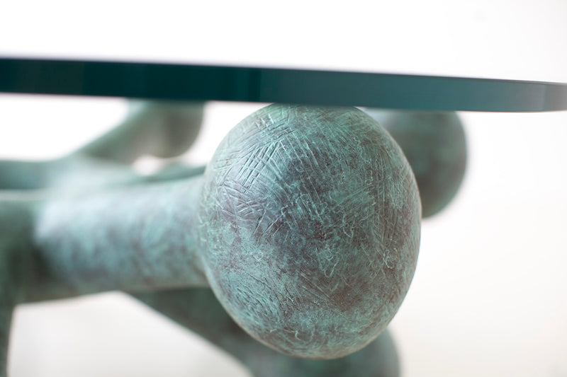 Angled view of the bronze coffee table with round glass top