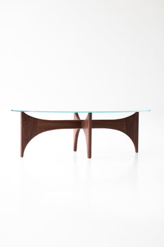 Angled view of the oval glass top coffee table with teak base