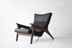Close-up of the leather armrest and walnut arm detail on a lounge chair