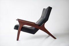 Front view of a walnut leather lounge chair showing its tailored upholstery