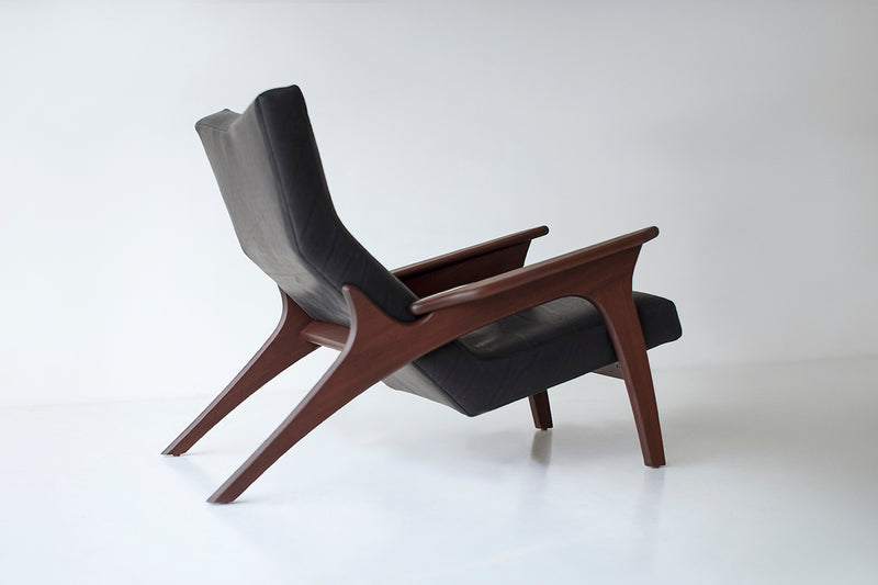 Full view of a walnut leather lounge chair against a white backdrop