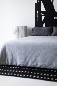 Whitewash red cedar stump nightstand beside a bed, close view