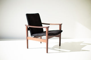 Close-up of the black leather upholstery and walnut joinery on the occasional chair