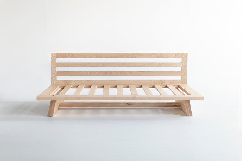 Close-up of the solid maple wood frame and natural finish on the Sabi daybed