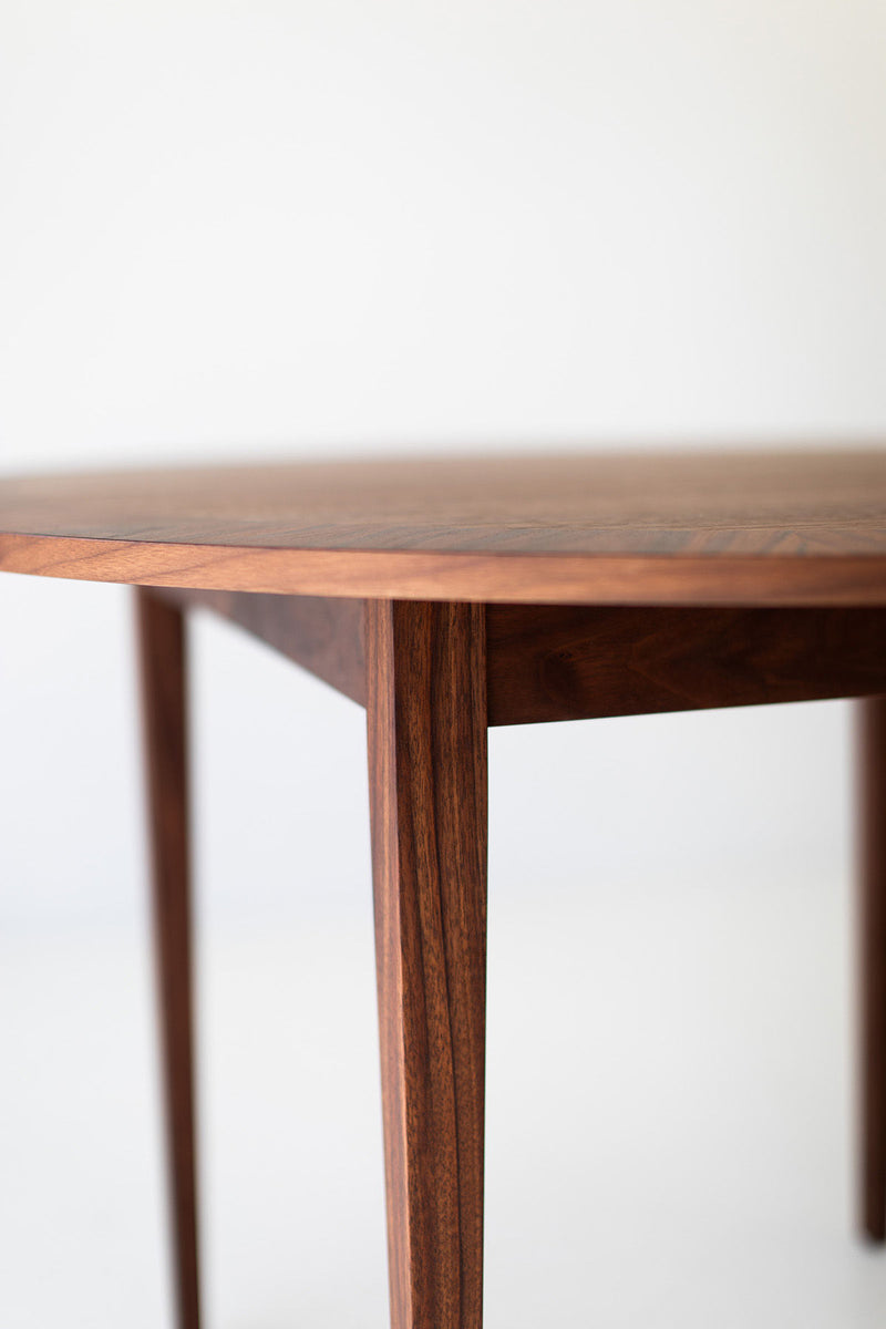 Modern round dining table with its leaf extended in a dining room
