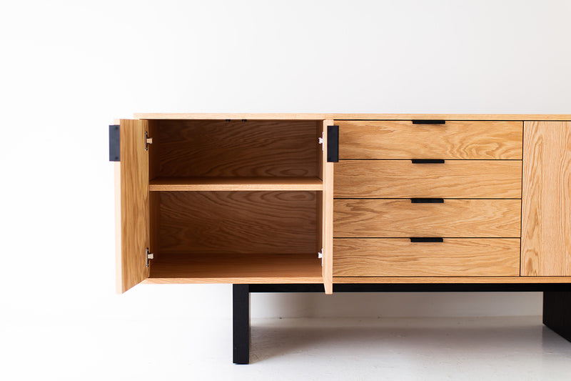 Angled view of the modern Baron oak credenza on its blackened base
