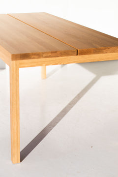 Angled view of the modern luxury split panel white oak dining table