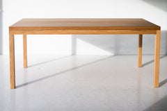 Modern luxury split panel white oak table styled in a bright dining space