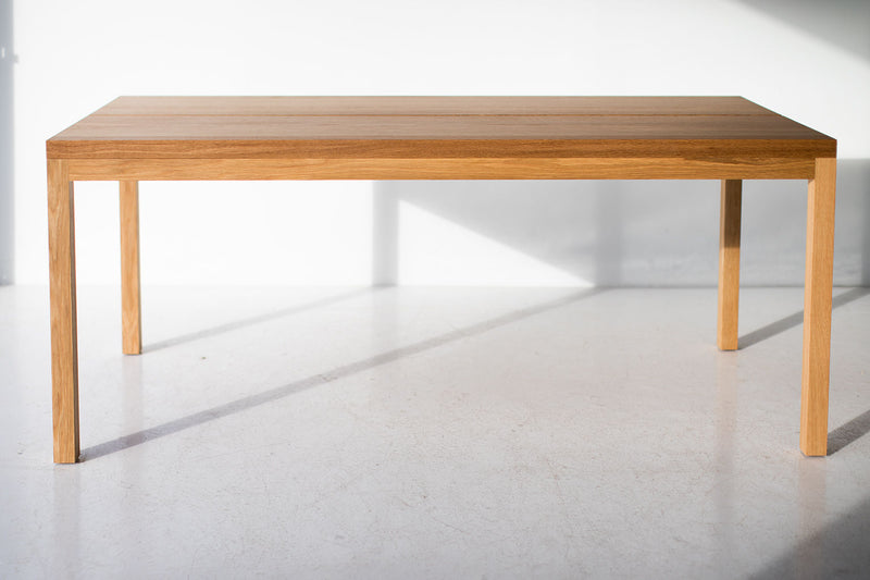 Modern luxury split panel white oak table styled in a bright dining space