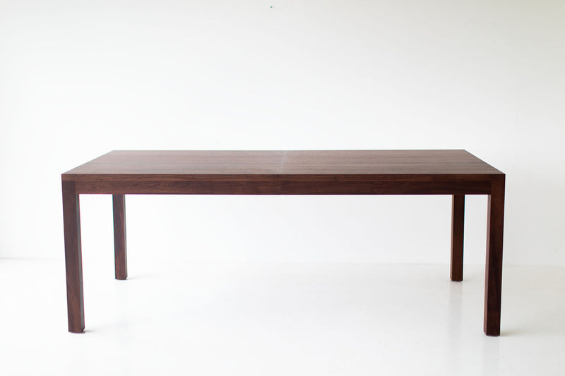 Modern walnut dining table with clean tapered legs and an extendable top
