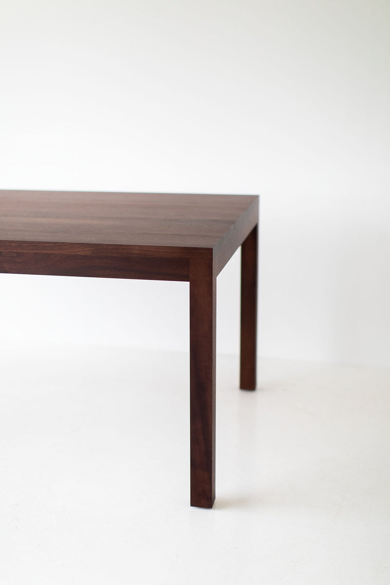 Angled view of the walnut dining table showing its extension leaves