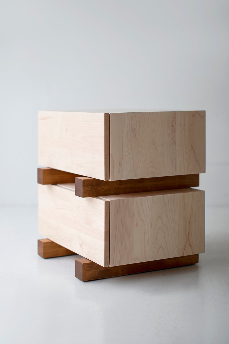 Modern maple nightstand styled with a lamp and decor in a bedroom