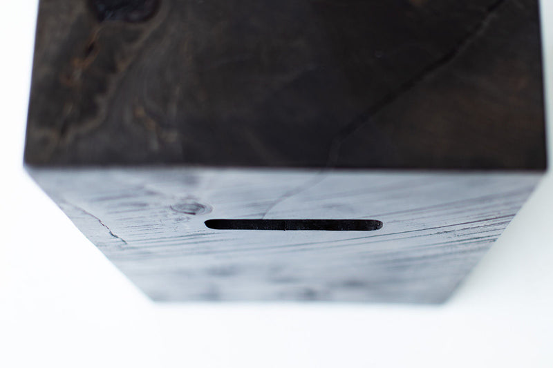 Modern wood side table with cutouts styled beside a sofa in a living room