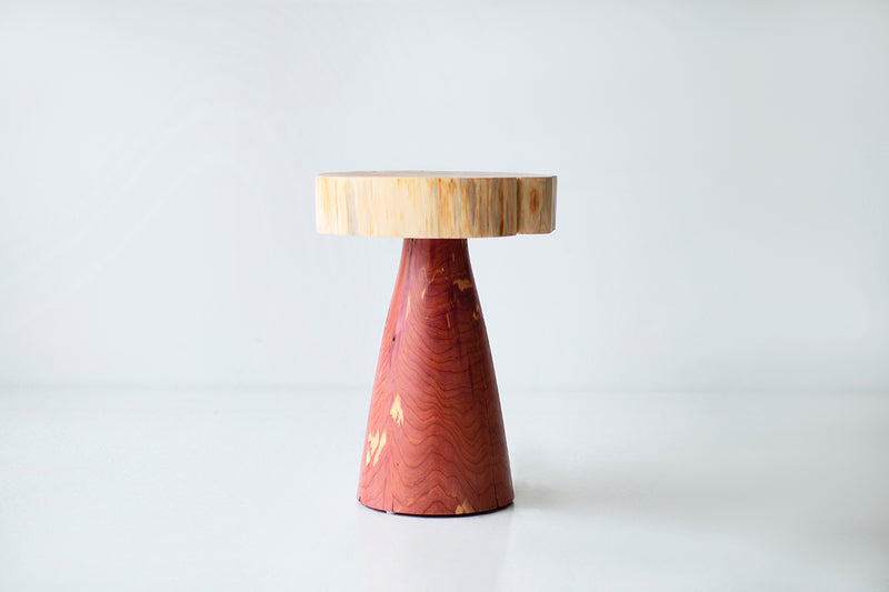 Red cedar stump side table styled next to a sofa in a living room