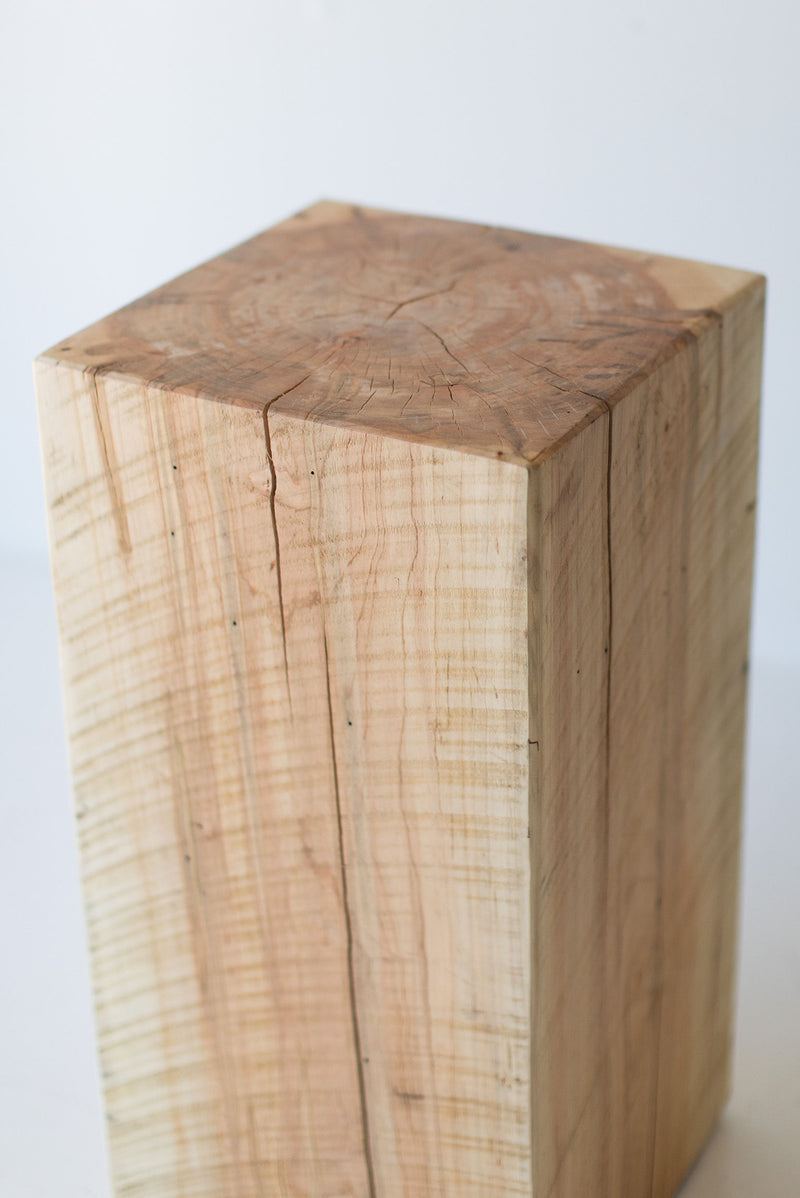 Tree stump side table styled next to a sofa in a modern living room