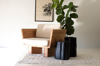 Black outdoor stump tables beside a lounge chair indoors