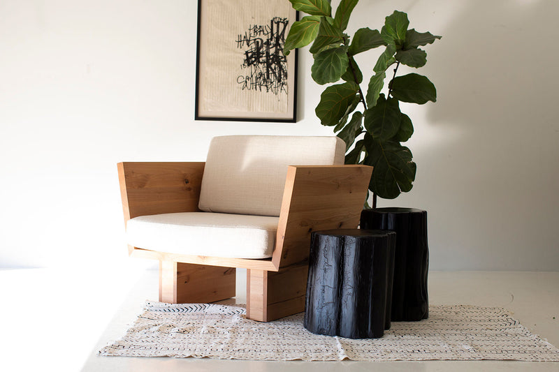 Black outdoor stump tables beside a lounge chair indoors