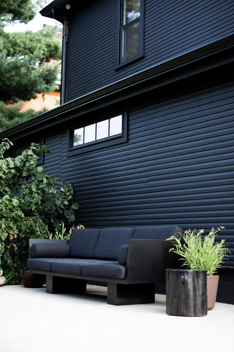 Black outdoor stump table on a patio beside an outdoor sofa