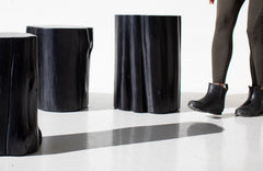 Two black outdoor stump tables with a person standing beside them