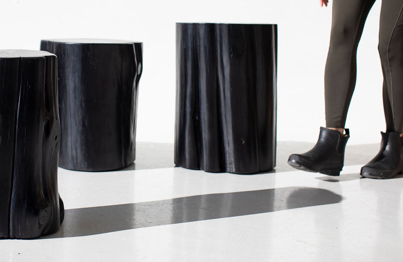Two black outdoor stump tables with a person standing beside them