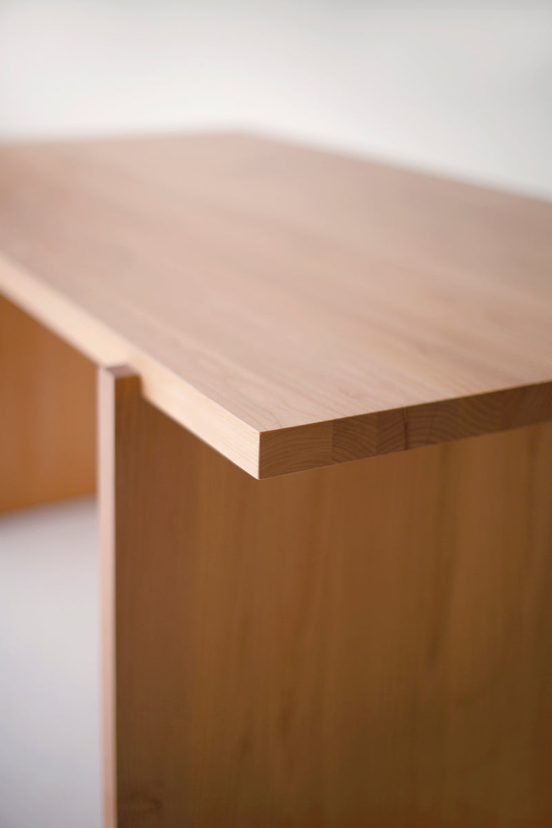 Front view of a natural wood Rockefeller dining table showing its architectural legs