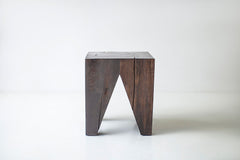 Solid wood stump table styled beside a sofa as an end table