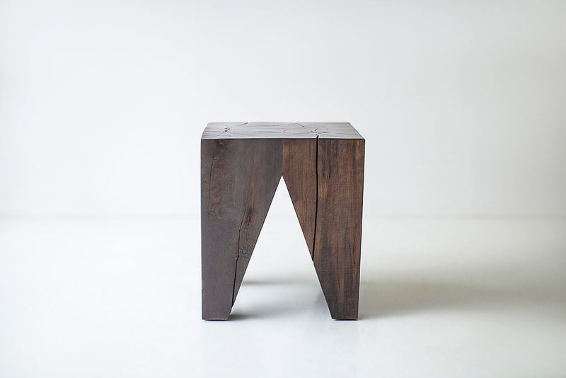 Solid wood stump table styled beside a sofa as an end table