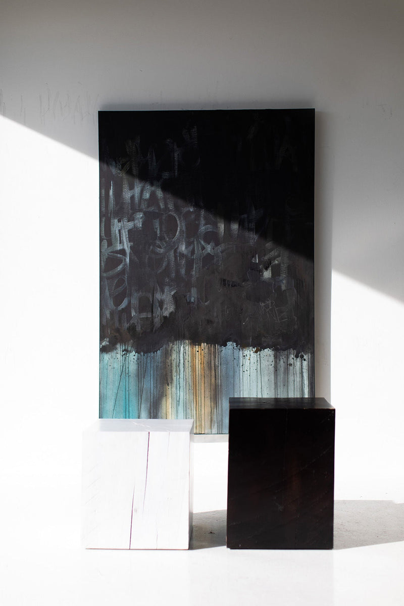 Whitewash and black maple block end tables in front of a painting