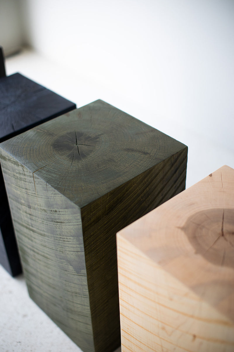 Army green stump table styled in a bright interior