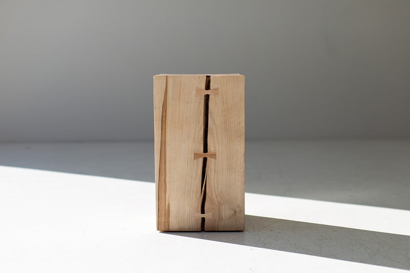Side profile of the wood side table with bowties showing its solid trunk form
