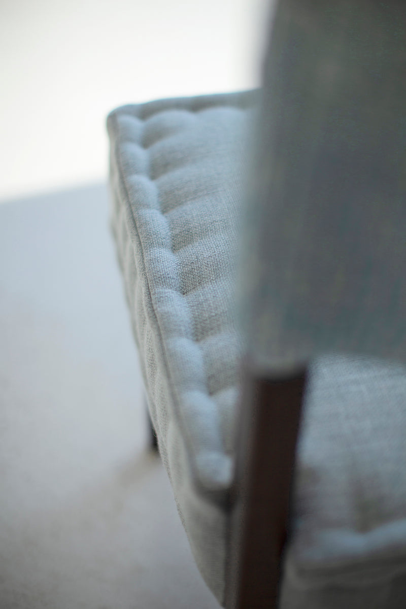 Side profile of a hand-stitched quilted dining chair on an oak frame