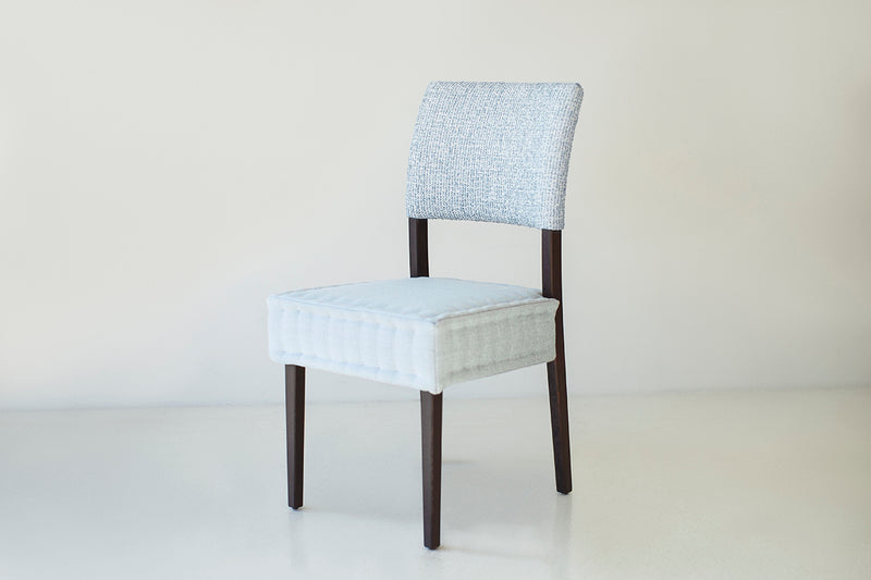 Angled view of an Arceo dining chair showing its sculpted oak legs