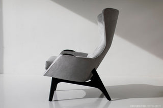 Side profile of the small wing chair in dark walnut, showing the sculpted splayed legs