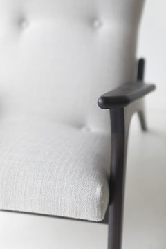 Close view of the sculpted dark walnut arm and grey upholstered seat