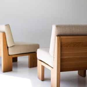 may include - modern luxury oak lounge chair with minimalist design, featuring clean lines and simple sleek shape. Chair sits in a clean white room with white floors. The overall aesthetic is modern. 05
