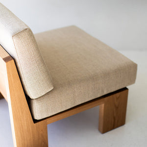 may include - modern luxury oak lounge chair with minimalist design, featuring clean lines and simple sleek shape. Chair sits in a clean white room with white floors. The overall aesthetic is modern. 06