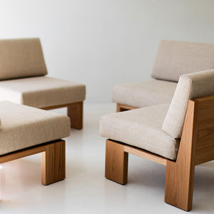 may include - modern luxury oak lounge chair with minimalist design, featuring clean lines and simple sleek shape. Chair sits in a clean white room with white floors. The overall aesthetic is modern. 09