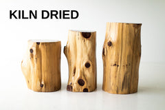 Three natural outdoor red cedar stump tables with a Kiln Dried label