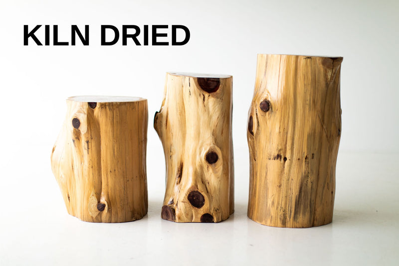 Three natural outdoor red cedar stump tables with a Kiln Dried label